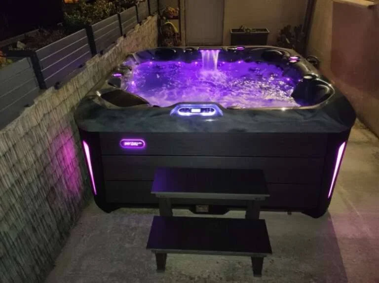 Spa extérieur éclairé de lumières violettes à la nuit tombée