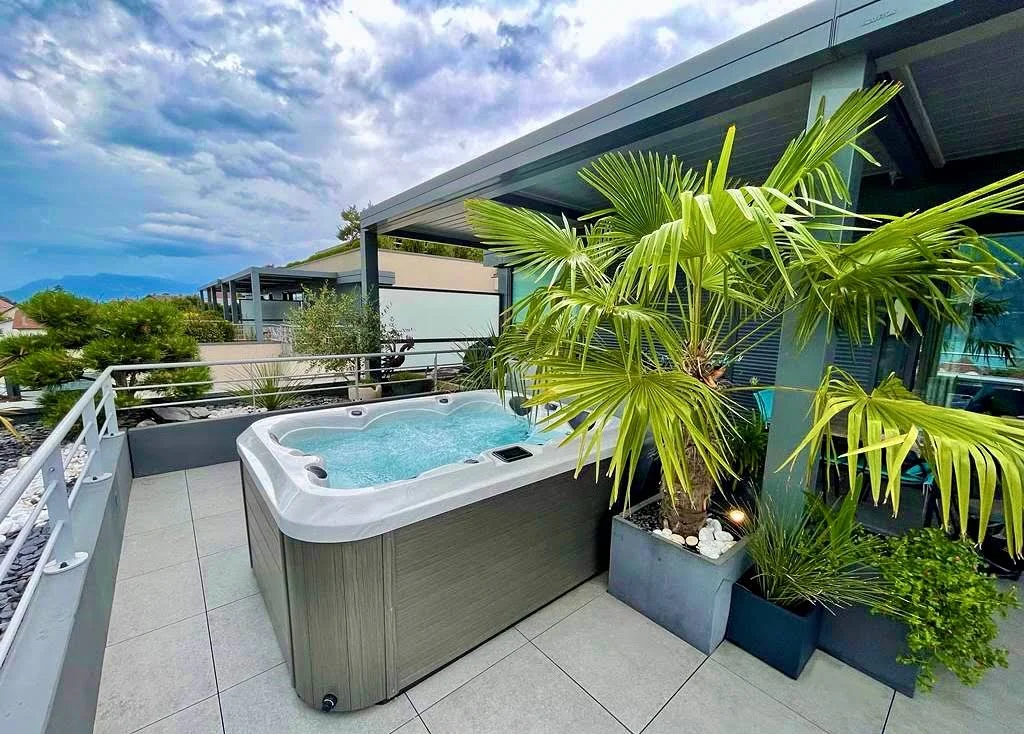 Spa installé sur une terrasse végétalisée avec des palmiers